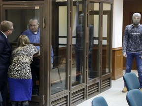 Paul Whelan, a former U.S. Marine, who was arrested in Moscow at the end of last year looks through a cage's glass as he speaks to his lawyers in a court room in Moscow, Russia, Tuesday, Jan. 22, 2019. The lawyer for Paul Whelan who is being held in Moscow on suspicion of spying, said Tuesday that classified Russian materials were found on him when he was arrested.