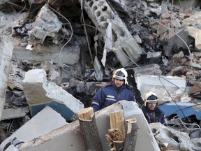 Emergency Situations employees working at the scene of a collapsed apartment building in Magnitogorsk, a city of 400,000 people, about 1,400 kilometers (870 miles) southeast of Moscow, Russia, Monday, Dec. 31, 2018. Russian emergency officials say that at least four people have died after sections of the apartment building collapsed after an apparent gas explosion in the Ural Mountains region.