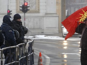 A protestor blows a horn, standing next to a police cordon during a protest against the change of the country's name outside the parliament building in Skopje, Macedonia, Wednesday, Jan. 9, 2019. Macedonian lawmakers are entering the last phase of debate on constitutional changes to rename their country North Macedonia as part of a deal with neighboring Greece to pave the way for NATO membership and eventually joining the European Union..