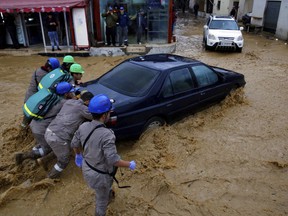 Civil Defense workers struggle to push a stranded car on a street in Beirut, Lebanon, Tuesday, Jan. 8, 2019. A strong storm and heavy rainfall turned streets in Lebanon into rivers of water and mud and paralyzed parts of the country. The government ordered schools shut with snow expected to fall across the country at altitudes of 600 meters.