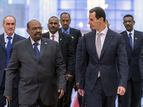 FILE - In this file photo released by the Syrian official news agency SANA Dec. 16, 2018, Syrian President Bashar Assad, right, meets with Sudan's President Omar Bashir in Damascus, Syria.  Assad has survived years of war and millions of dollars in money and weapons aimed at toppling him. Now after nearly eight years of conflict, he is poised to be readmitted to the fold of Arab nations, a feat once deemed unthinkable as he brutally crushed a years-long uprising against his family's rule.  (SANA via AP, File)