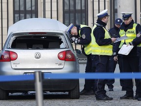 Police officers examine a car in the driveway to the Presidential Palace in Warsaw, Poland, Tuesday, Jan. 22, 2019 after a man rammed the car into a metal barrier protecting the driveway. The man was driving the wrong way and hit a policeman who was trying to stop him before ramming into the barrier.