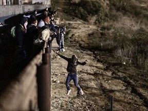 A migrants jumps the border fence to get into the U.S. side to San Diego, Calif., from Tijuana, Mexico, Tuesday, Jan. 1, 2019. Discouraged by the long wait to apply for asylum through official ports of entry, many migrants from recent caravans are choosing to cross the U.S. border wall and hand themselves in to border patrol agents.