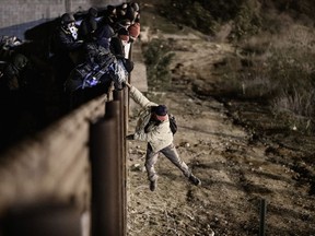 A migrant jumps the border fence to get into the U.S. side to San Diego, Calif., from Tijuana, Mexico, Tuesday, Jan. 1, 2019. Discouraged by the long wait to apply for asylum through official ports of entry, many migrants from recent caravans are choosing to cross the U.S. border wall and hand themselves in to border patrol agents.