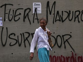 A woman walks past graffiti that says in Spanish: "Get out Maduro. Usurper," referring to President Nicolas Maduro in Caracas, Venezuela, Thursday, Jan. 24, 2019. Venezuelans headed into uncharted political waters Thursday, with the young leader of a newly united and combative opposition claiming to hold the presidency and Maduro digging in for a fight with the Trump administration.