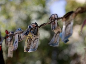 Discontinued Venezuelan bank notes hang above a cigarette stand in the San Jose del Avila neighborhood in Caracas, Venezuela, Tuesday, Jan. 22, 2019. Working class neighborhoods in Venezuela's capital sifted through charred rubble and smoldering trash on Tuesday, following a day of isolated protests in response to the arrest of National Guardsmen who mounted an uprising against President Nicolas Maduro.