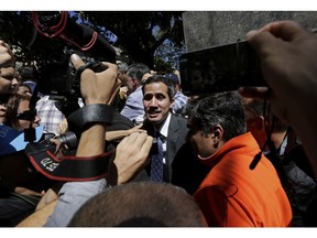 Supporters of opposition leader Juan Guaido and the press gather around him as he leaves a public plaza where he spoke in Caracas, Venezuela, Friday, Jan. 25, 2019. The 35-year-old lawmaker's whereabouts had been a mystery since he was symbolically sworn in Wednesday before tens of thousands of cheering supporters, promising to uphold the constitution and rid Venezuela of Maduro's dictatorship.