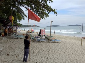 A man raises a red flag indicating rough weather conditions in Chaweng beach, Koh Samui, Thailand, Thursday, Jan. 3, 2019. Thai weather authorities are warning that a tropical storm will bring heavy rains and high seas to southern Thailand and its famed beach resorts.