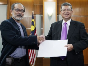 Malaysia Foreign Minister Saifuddin Abdullah, right, receive a memorandum from Mohd Mazarin Bin Ismail, chairman of Boycott, Divestment and Sanctions (BDS) Malaysia, before a press conference in Putrajaya, Malaysia, Wednesday, Jan. 16, 2019. Malaysia's foreign minister says the government will not budge over a ban on Israeli athletes in para swimming competition and decided that the country will not host any events in future involving Israel.