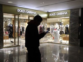 FILE - In this Nov. 21, 2018, file photo, a man walks past an outlet of Dolce & Gabbana in Beijing. Chinese model Zuo Ye in advertisements for Italian fashion line Dolce & Gabbana that were widely derided in the country apologized for her appearance in the campaign.
