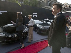 FILE - In this April 22, 2014, file photo. Tesla Motors CEO Elon Musk, right, looks on as a set of Tesla Model S sedans are delivered to its first customers in China at an event in Beijing. Musk said Monday, Jan. 7, 2019 on twitter that the automaker is breaking ground for a Shanghai factory and will start production of its Model 3 by the end of the year.