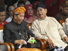 FILE - In this Sept. 23, 2018 file photo, Indonesian President Joko Widodo, left, and his contender Prabowo Subianto share a light moment during a ceremony marking the kick off of the campaign period for next year's election in Jakarta, Indonesia. Echoing the campaign tactics of Donald Trump, former Indonesian Gen. Prabowo Subianto says his country, the world's third-largest democracy, is in dire shape and he is the leader who will restore it to greatness.