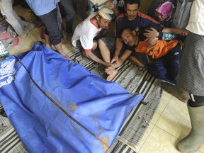 A man reacts near a body bag containing the body of his relative who was killed by a landslide in Sirnaresmi, West Java, Indonesia, Tuesday, Jan. 1, 2019. The landslide triggered by torrential rain has killed a number of people and left dozens others missing on Indonesia's main island of Java. (AP Photo)