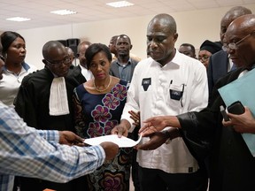 Accompanied by his wife and his lawyers, Congo opposition candidate Martin Fayulu receives the receipt after petitioning the constitutional court following his loss in the presidential elections in Kinshasa, Congo, Saturday Jan. 12, 2019. The ruling coalition of Congo's outgoing President Joseph Kabila has won a large majority of national assembly seats, the electoral commission announced Saturday, while the presidential election runner-up was poised to file a court challenge alleging fraud.