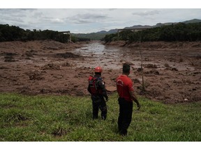 Civil firefighters survey a destroyed rail bridge two days after a dam collapse in Brumadinho, Brazil, Sunday, Jan. 27, 2019. Brazilian officials on Sunday suspended the search for potential survivors of a dam collapse that has killed at least 40 people amid fears that another nearby dam owned by the same company was also at risk of breaching.