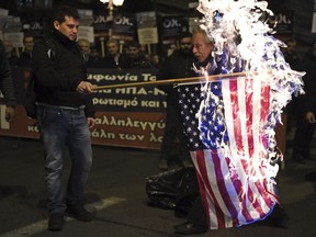 Members of the Greek Communist party set ablaze a United States flag during a rally against Prespa Agreement in Athens, Thursday, Jan. 24, 2019. Greek lawmakers are debating a historic agreement aimed at normalising relations with Macedonia in a stormy parliamentary session scheduled to culminate in a Friday vote.