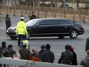 Spectators watch as security officials stand guard while a Mercedes limousine in a motorcade believed to be carrying North Korean leader Kim Jong Un passes along a street in Beijing, Wednesday, Jan. 9, 2019. North Korean state media reported Tuesday that Kim is making a four-day trip to China in what's likely an effort by him to coordinate with his only major ally ahead of a summit with U.S. President Donald Trump that could happen early this year.