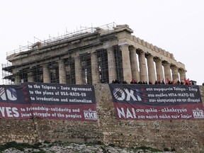 Members of Greece's Communist Party stand on the ancient Acropolis Hill over giant banners protesting against the Prespa Agreement in front of the ancient Parthenon temple, in Athens, Thursday, Jan. 24, 2019. Greek lawmakers are debating a historic agreement aimed at normalizing relations with Macedonia in a stormy parliamentary session scheduled to culminate in a Thursday vote, while opponents have announced a series of protests.