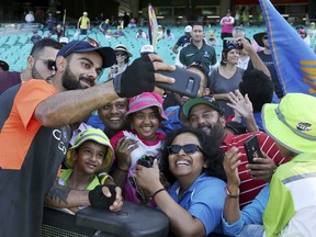 India's Virhat Kohli, second left, takes a photo with fans ahead of play on the second day of their cricket test match against Australia in Sydney, Friday, Jan. 4, 2019.
