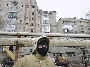 An Emergency services worker at the scene of the destroyed top floor of a apartment building in the city of Shakhty, Russia, Monday, Jan. 14, 2019. A suspected gas explosion at an apartment building in southern Russia killed at least one person and injured two others early Monday, authorities said. (AP Photo)