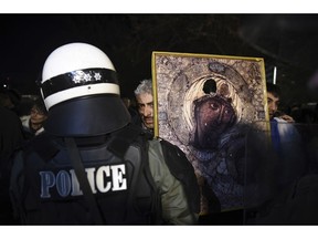 A protester holds a religious icon in front of a police officer during a rally in the northern port city of Thessaloniki, Greece, Sunday, Jan. 27, 2019. About 250 protesters gathered to protest against the deal which will rename Macedonia, Greece's northern neighbor, "North Macedonia". The protest is being staged on the occasion of the visit of Greek President Prokopis Pavlopoulos in Thessaloniki to attend a concert commemorating the Jewish Holocaust give a keynote speech.