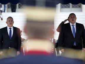 Newly appointed Defense Minister Evangelos Apostolakis, left, and outgoing Panos Kammenos, sing the national anthem during the handover ceremony in Athens, Tuesday, Jan. 15, 2019. The 62-year-old retired admiral left his post as head of the country's armed forces to replace Panos Kammenos, leader of a small nationalist party, who withdrew from the government coalition at the weekend over disagreement on a proposed deal between Greece and neighbor Macedonia. Greece's parliament has scheduled a confidence vote for late Wednesday following the collapse of Prime Minister Alexis Tsipras' governing coalition over a proposed deal to end a decades-old dispute with Macedonia.