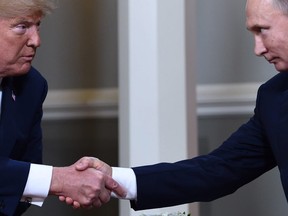 In this file photo taken on July 16, 2018, U.S. President Donald Trump (L) and Russian President Vladimir Putin shake hands ahead a meeting in Helsinki.