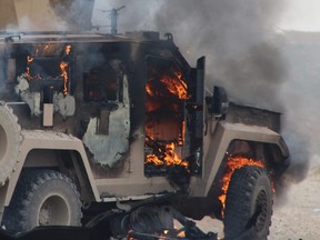 A military vehicle on fire at the scene of a suicide car bomb attack on a military convoy on a road in Syria's northeastern Hasakeh province. The attack killed five members of a Kurdish-led force accompanying U.S.-led coalition troops on January 21, 2019.