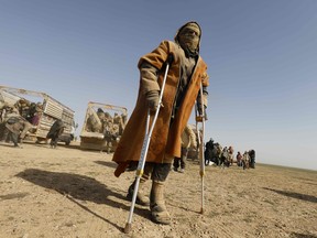 A man uses crutches to walk as people who fled battles between Syrian Democratic Forces (SDF) and fighters from ISIL in the Syrian village of Baghuz, arrive after crossing a desert  in the back of a truck to a region controlled by the SFD on January 26, 2019.
