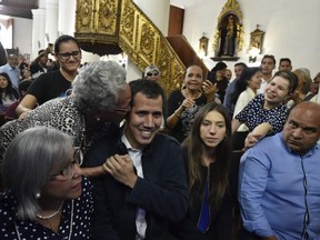 Venezuela's National Assembly head and self-proclaimed "acting president" Juan Guaido, accompanied by his wife Fabiana Rosales (2-R) and his mother Norka Marquez (L), is greeted by a woman during a mass at the San Jose church in Caracas on January 27, 2019.