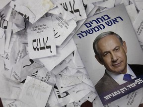 In this Wednesday, March 18, 2015 file photo, an election campaign poster with the image of Israeli Prime Minister Benjamin Netanyahu lies among ballot papers at his party's election headquarters, in Tel Aviv.