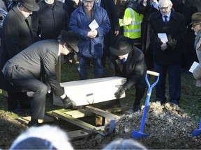 A coffin with the remains of six unidentified Holocaust victims is buried at the United Synagogue's New Cemetery in Bushey, England, Sunday Jan. 20, 2019. The remains of six unidentified Holocaust victims have been buried at a Jewish cemetery after spending years in storage at a British museum. The Imperial War Museum found the ashes and bone fragments during a stock-taking last year. Hundreds of mourners watched as the remains of five adults and a child were buried at a cemetery outside London, in a coffin with earth from Israel.