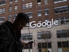 In this file photo dated Monday, Dec. 17, 2018, a man using a mobile phone walks past Google offices in New York.