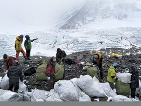 In this May 8, 2017, file photo released by Xinhua News Agency, people collect garbage at the north slope of the Mount Qomolangma in southwest China's Tibet Autonomous Region. China announced Monday, Jan. 21, 2019 that it plans to cut the number of climbers attempting to scale Mount Everest from the north by 1/3 this year as part of plans for a major cleanup on the world's highest peak.