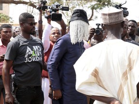 In this photo taken Friday, Jan. 18, 2019, Anas Arimiyaw Anas, investigative journalist, centre, with his face covered attends the funeral of fellow investigative journalist Ahmed Hussein-Suale, who was shot dead by gunmen on a motorbike on Wednesday night, in Accra, Ghana.