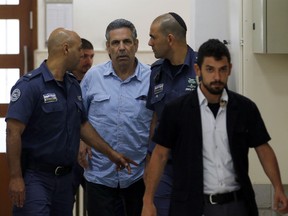 In this Thursday July 5, 2018 file photo, former Israeli cabinet minister indicted on suspicion of spying for Iran, Gonen Segev, centre, is escorted by prison guards as he arrives at court in Jerusalem, Israel. Segev will serve 11 years in prison as part of a plea bargain with authorities, Israel's justice ministry said Wednesday.