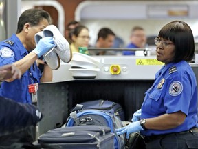 Transportation Security Administration officers assist travellers with luggage through a security screening area during a partial federal government shutdown Monday, Dec. 31, 2018, in SeaTac, Wash.