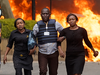 Security forces help civilians flee the scene as cars burn behind, at a hotel complex in Nairobi, Kenya, on Jan. 15, 2019, after terrorists attacked an upscale hotel complex in Kenya’s capital.