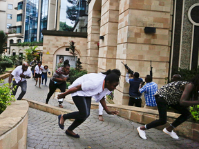 Civilians flee as security forces aim their weapons at the buildings of a hotel complex in Nairobi, Kenya, Jan. 15, 2019, after extremists launched a deadly attack.