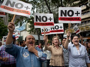 People holding signs that read in Spanish: "No more dictatorship" take part in a walkout against President Nicolas Maduro, in Caracas, Venezuela, on Jan. 30, 2019.