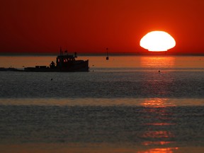 In this Sept. 13, 2017, file photo, a lobster fishing boat heads out to sea at sunrise off shore from Portland, Maine.