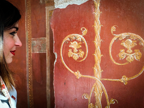 A woman looks at a fresco at the Schola Armaturarum building in Pompeii, Italy. A 2,000-year-old building where gladiators trained in ancient Pompeii is now open to visitors, eight years after its collapse following rainfall.