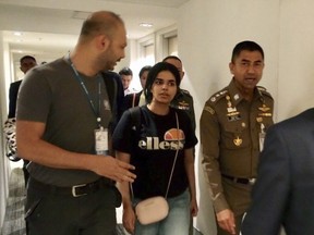 In this photo released by the Immigration Police, Chief of Immigration Police Maj. Gen. Surachate Hakparn, right, walks with Saudi woman Rahaf Mohammed Alqunun before leaving the Suvarnabhumi Airport in Bangkok Monday, Jan. 7, 2019. A Saudi woman who says she is fleeing abuse by her family and wants asylum in Australia has sent out desperate pleas for help over social media. Rahaf Mohammed Alqunun, 18, began posting on Twitter late Saturday after her passport was taken away when she arrived on a flight from Kuwait.