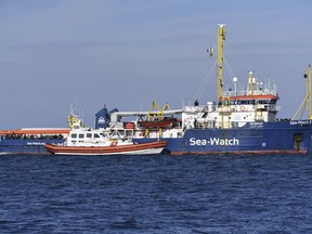 A coastguard boat approaches the German humanitarian group's rescue boat Sea Watch 3, to deliver food and blankets for the cold, off the coast of Syracuse, Italy, Sunday, Jan. 27, 2019. The Italian coast guard is bringing socks, shoes, bread and fruit to 47 migrants who have been stranded at sea for nine days aboard a German ship.