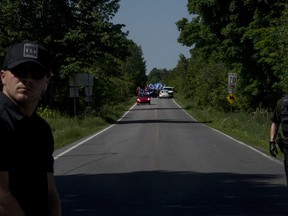 A large crowd is escorted along Chemin Roxham during a protest against illegal boarder crossing Saint-Bernard-de-Lacolle, Quebec, June 3, 2018.