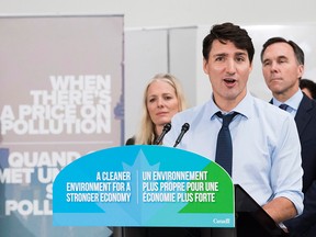 Prime Minister Justin Trudeau speaks about the Liberal government's new federally imposed carbon tax, while Environment Minister Catherine McKenna and Finance Minister Bill Morneau listen from behind him, at Humber College in Toronto on Oct. 23, 2018.