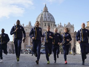 Athletes of the Athletic Vatican sports team run for the media in front of St. Peter's basilica, at the Vatican, Thursday, Jan. 10, 2019.