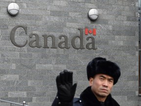 A guard attempts to block photos from being taken outside the Canadian embassy in Beijing on January 27, 2019.