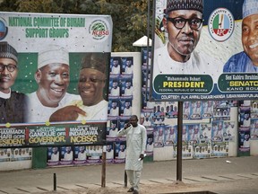 A man takes a call on his cellphone as he stands between two billboards showing Nigeria's President Muhammadu Buhari and other party officials, in Kano, northern Nigeria Tuesday, Feb. 26, 2019. Buhari's election lead grew on Tuesday during a second day of announcing state-by-state election results in Africa's largest democracy.