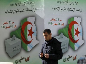 In this Feb. 5, 2019, photo, a man walks past a poster asking citizen to register to vote in Algiers. More than 180 people want to run for president of Algeria in the April election, amid growing uncertainty about whether President Abdelaziz Bouteflika, infirm following a stroke, is fit for yet another term after 20 years in charge of this gas-rich North African nation.